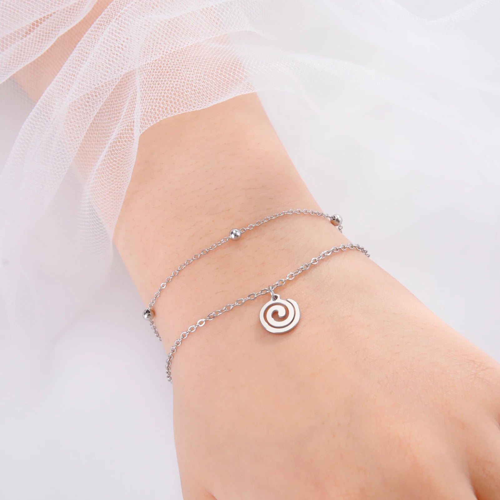 Goudkleurige armband met kleine zilveren spiraalbedel