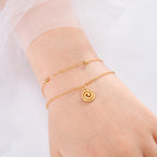 Goudkleurige armband met kleine gouden spiraalbedel
