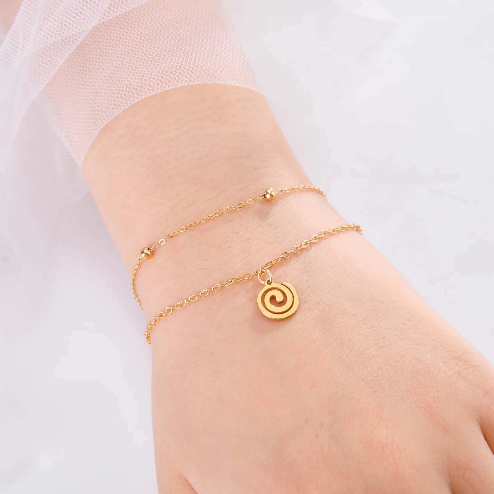 Goudkleurige armband met kleine gouden spiraalbedel