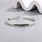 Open manchette armband met zilverkleurige veer