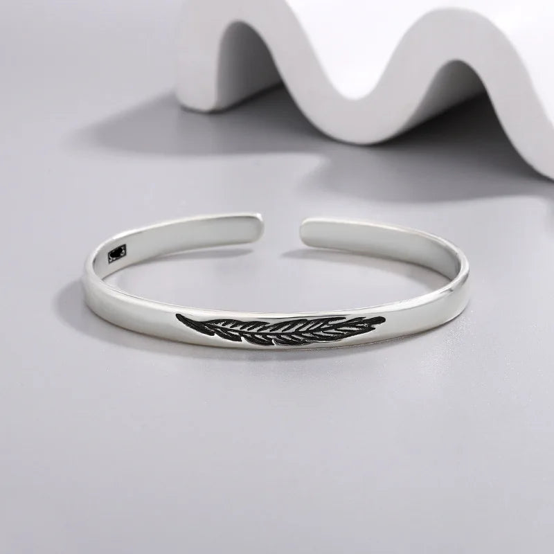 Open manchette armband met zilverkleurige veer