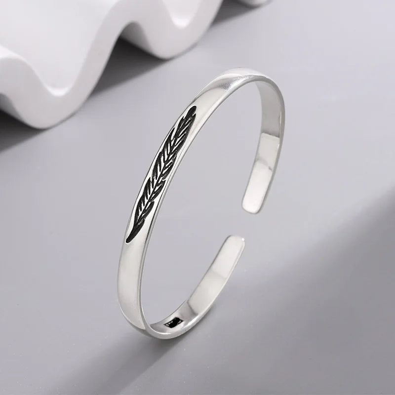 Open manchette armband met zilverkleurige veer